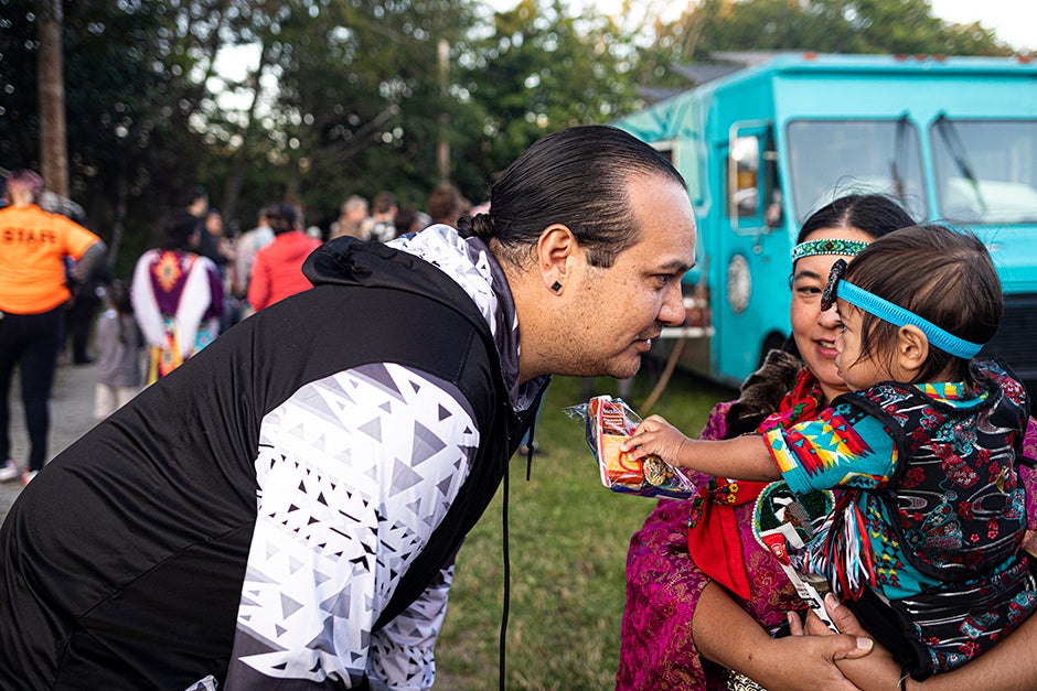 A family of three stand together at a community event