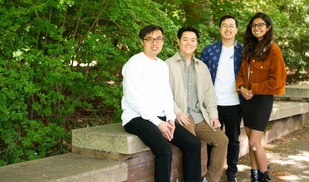 A group of graduate UW MSIM students gathered around a bench on campus.