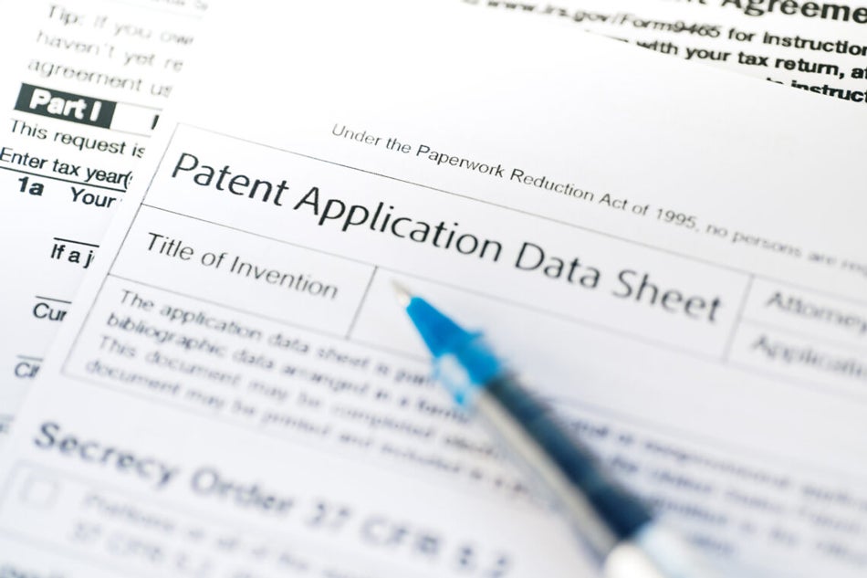 A pen lies on top of a stack of patent application forms.